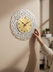 Decorative wall clock with intricate design being attached to a wall.